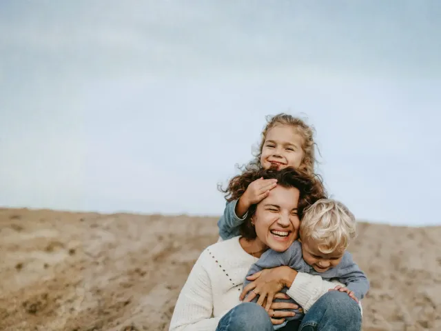 Moeder met twee kinderen aan het strand