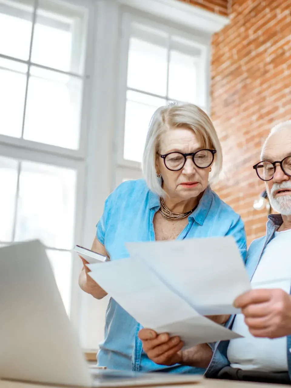 Ouder koppel dat kijkt naar documenten en computer