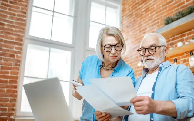 Ouder koppel dat kijkt naar documenten en computer